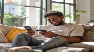 Homem sorridente usando smartphone em uma sala moderna para abrir conta bancária pelo celular.